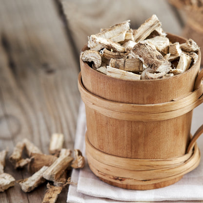 Organic marshmallow root for tea displayed in a wooden container with loose pieces on a table
