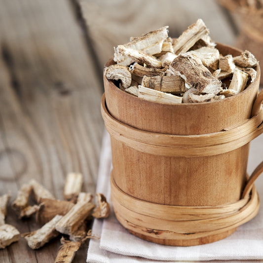 Organic marshmallow root for tea displayed in a wooden container with loose pieces on a table